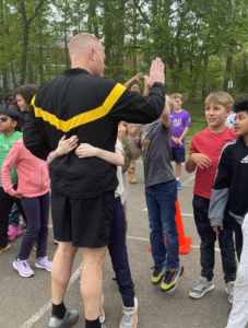 students hugging and high fiving a member of the military as they prepare for the fun run